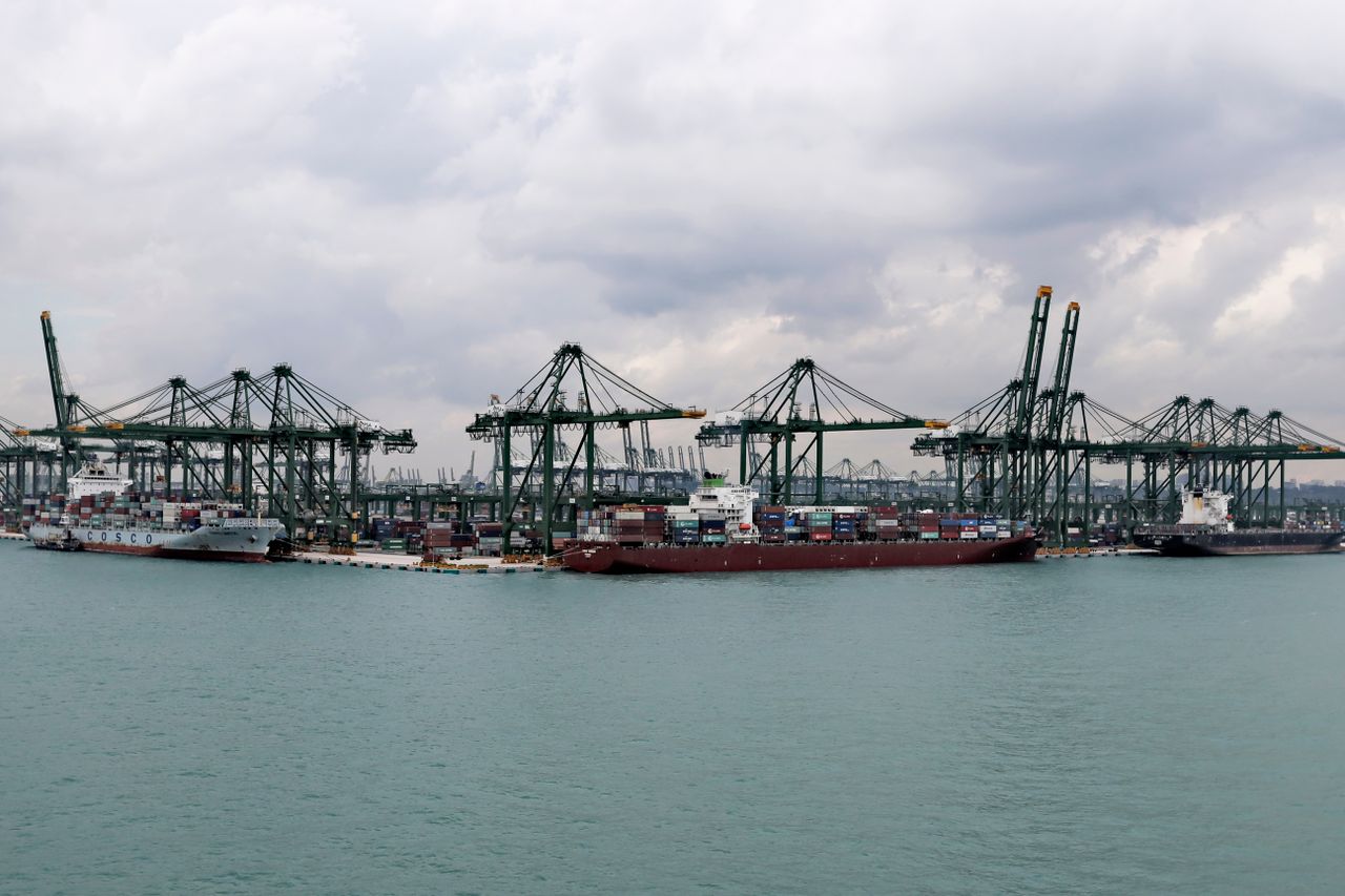 A bustling port with container ships and cranes under a cloudy sky, showcasing maritime logistics.